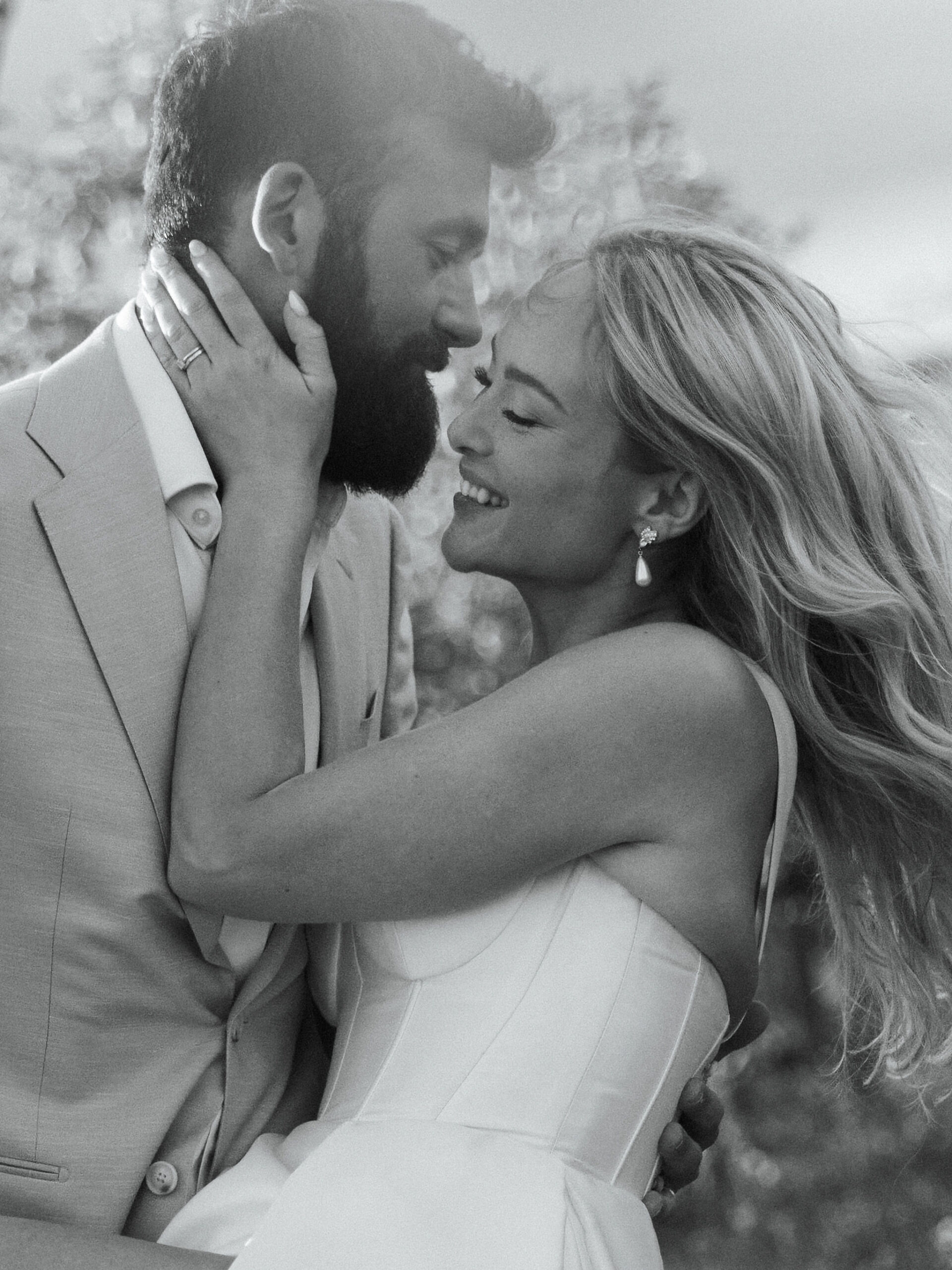Bride and groom embracing and smiling in an intimate black-and-white moment outdoors