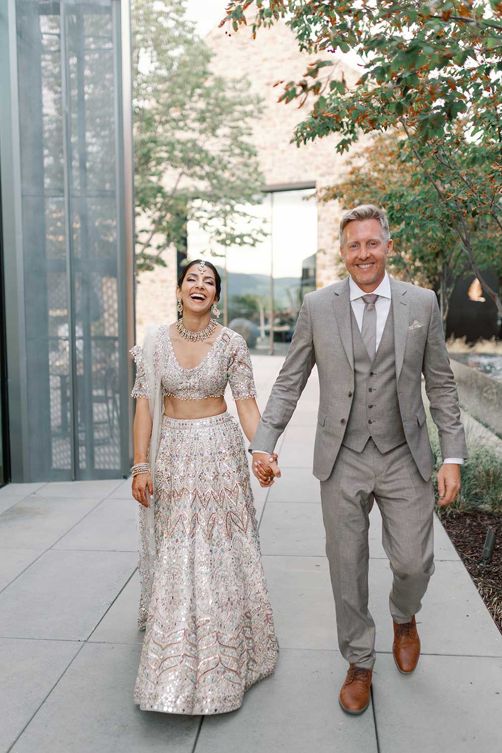 Couple walking hand-in-hand and smiling during their wedding at CedarCreek Estate Winery in Kelowna, BC, planned by Kasha May Weddings.