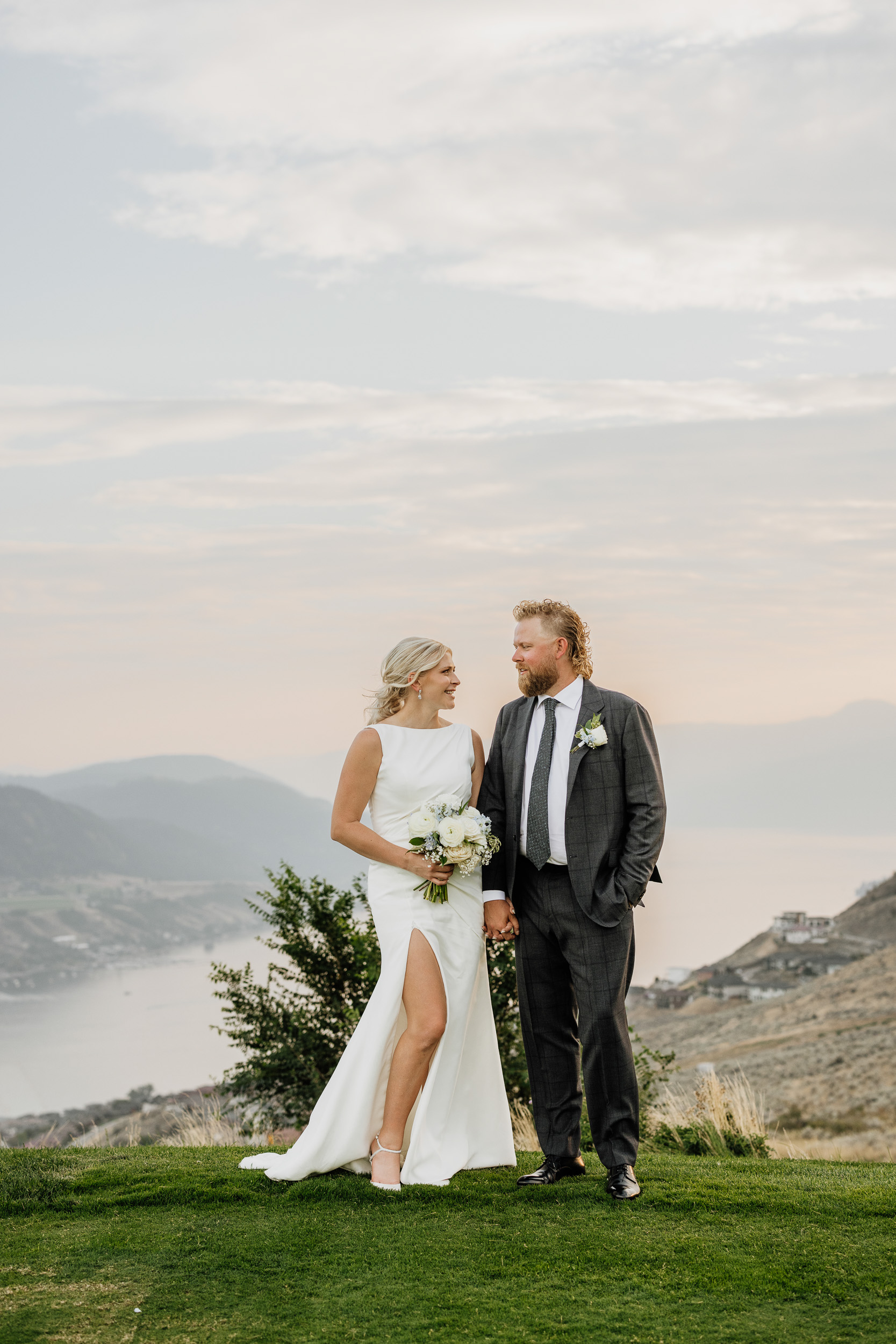 Marlee and Jamie hold hands during their wedding portraits at The Rise Resort in Vernon, BC, overlooking the Okanagan Valley at sunset.