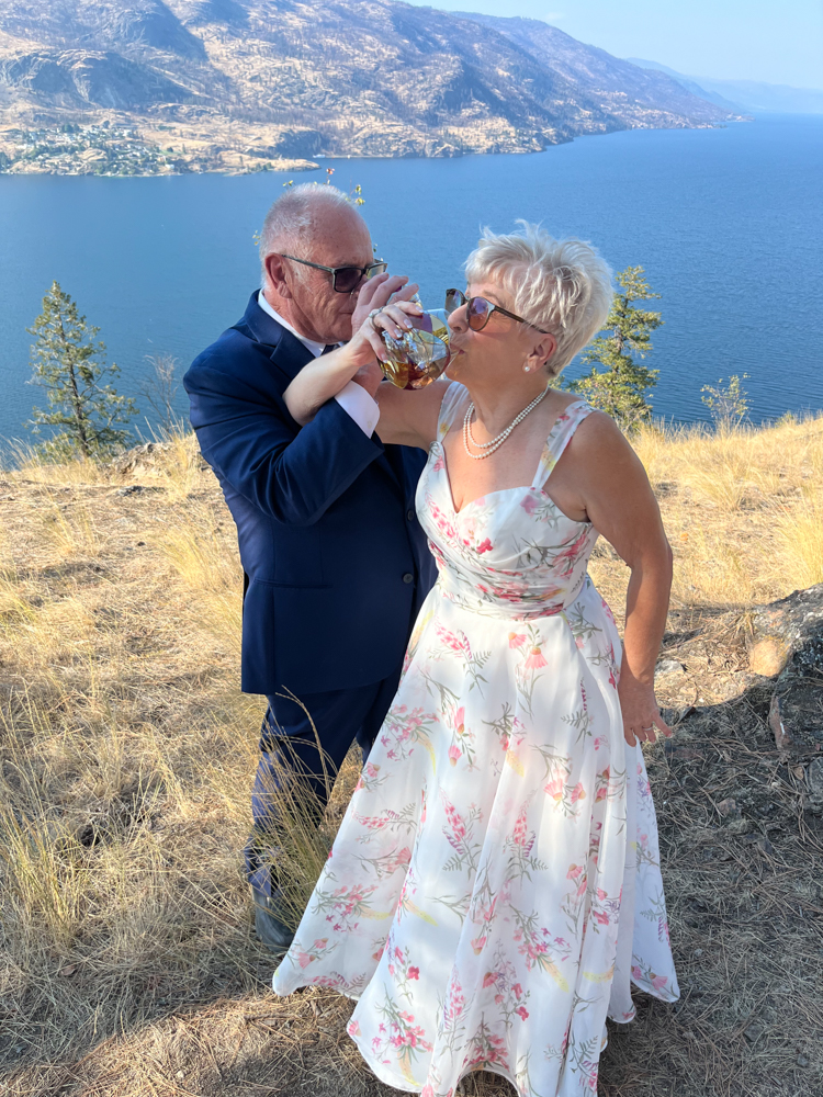 Bonnie and Rob share a joyful drink overlooking Okanagan Lake after their elopement ceremony atop Knox Mountain in Kelowna, BC.